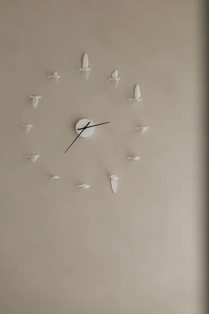 Wandklok met witte vogeltjes tegen een microcement wand, Nieuwbouwwoning in Roeselare, interieur Laura Calleeuw