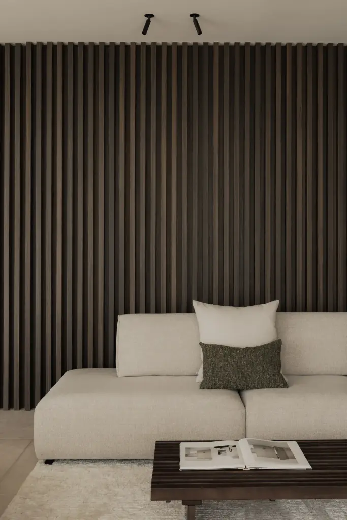 Woonkamer met hoekzetel, salontafel en lamellenwand in donker hout, Nieuwbouwwoning in Roeselare, interieur Laura Calleeuw