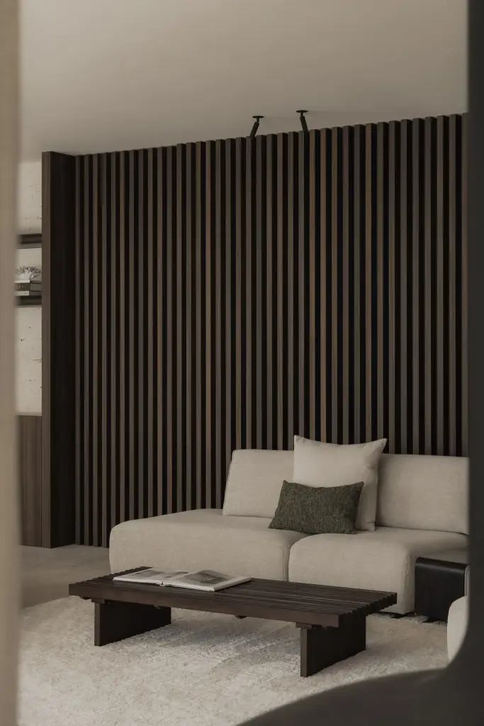 Woonkamer met hoekzetel, salontafel en lamellenwand in donker hout, Nieuwbouwwoning in Roeselare, interieur Laura Calleeuw