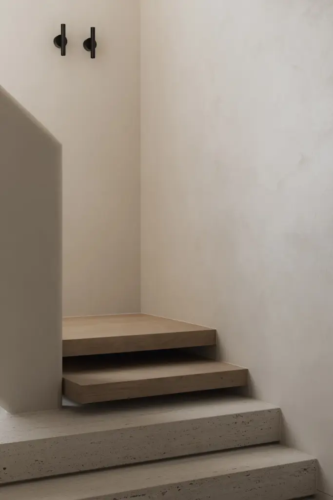 Zwevende eikenhouten trap met travertijn treden en gestucte wand, Nieuwbouwwoning in Roeselare, interieur Laura Calleeuw