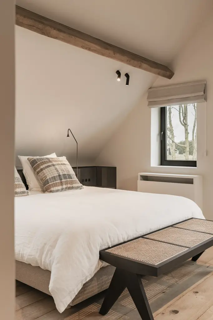 Bed met rotan bankje onder een eikenhouten balk, Schuur in Westkapelle, interieur Laura Calleeuw