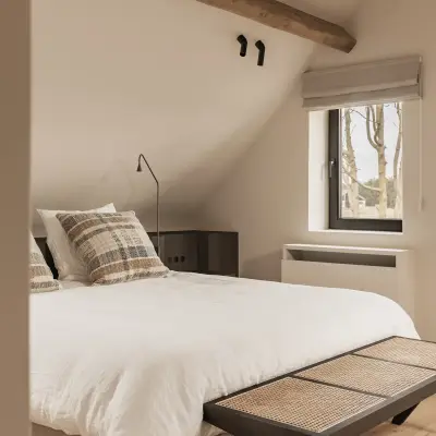 Bed met rotan bankje onder een eikenhouten balk, Schuur in Westkapelle, interieur Laura Calleeuw