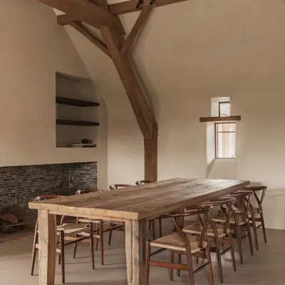 Eetkamer met lange eikenhouten tafel, wishbone stoelen en klein raam, Schuur in Westkapelle, interieur Laura Calleeuw