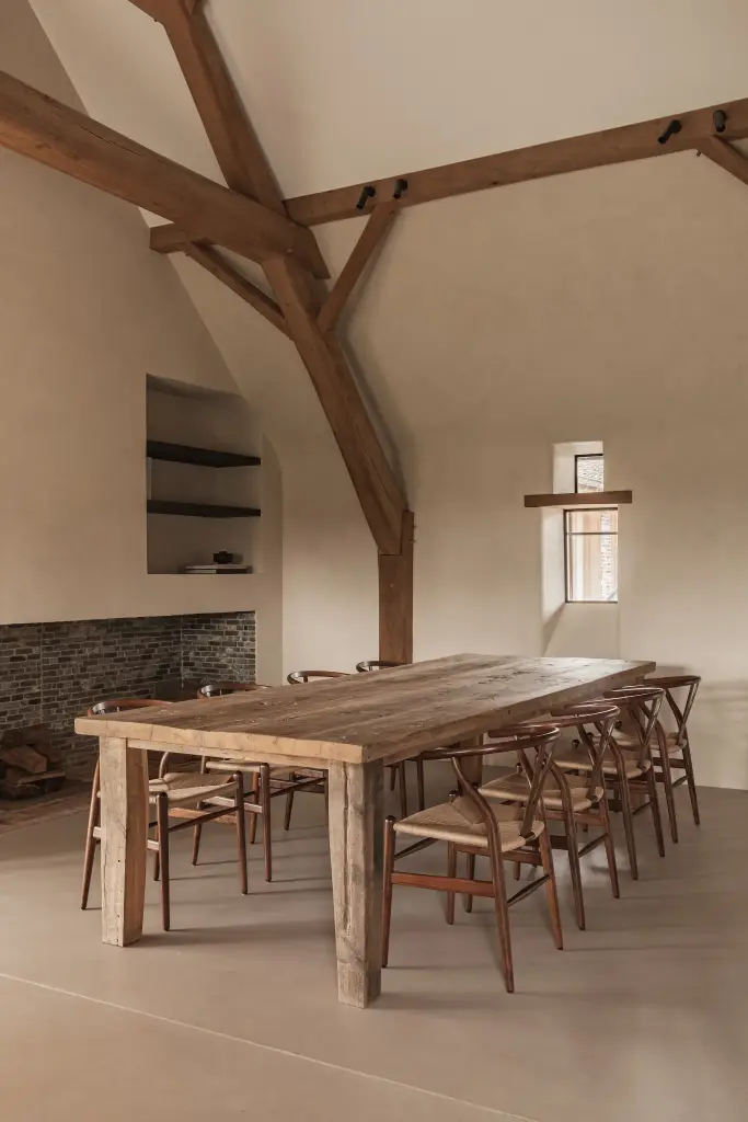 Eetkamer met lange eikenhouten tafel, wishbone stoelen en klein raam, Schuur in Westkapelle, interieur Laura Calleeuw