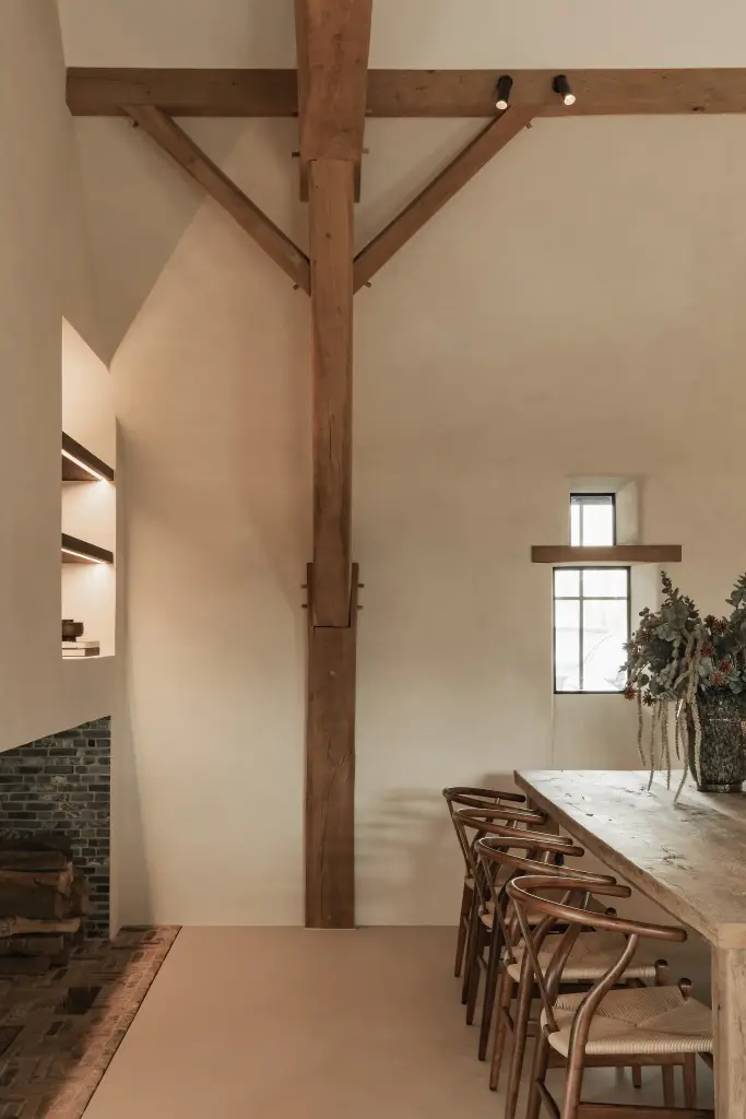 Eetkamer met lange eikenhouten tafel, wishbone stoelen en klein raam, Schuur in Westkapelle, interieur Laura Calleeuw