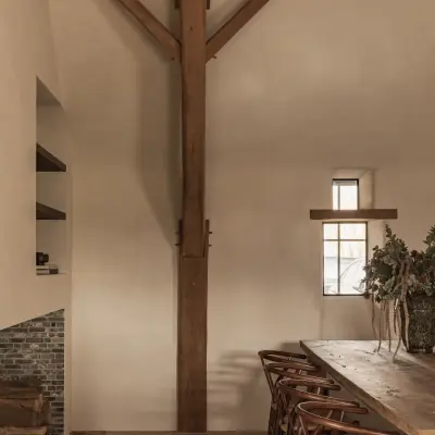 Eetkamer met lange eikenhouten tafel, wishbone stoelen en klein raam, Schuur in Westkapelle, interieur Laura Calleeuw