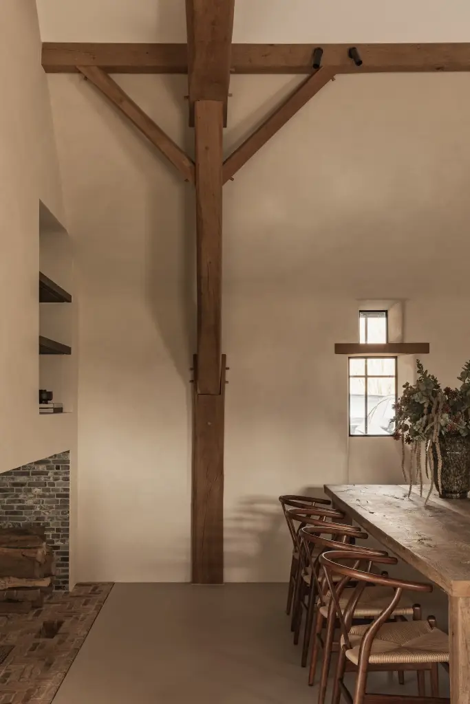 Eetkamer met lange eikenhouten tafel, wishbone stoelen en klein raam, Schuur in Westkapelle, interieur Laura Calleeuw