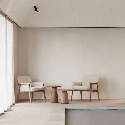Zithoek met fauteuils en houten bijzettafel naast het zwembad, Schuur in Westkapelle, interieur Laura Calleeuw