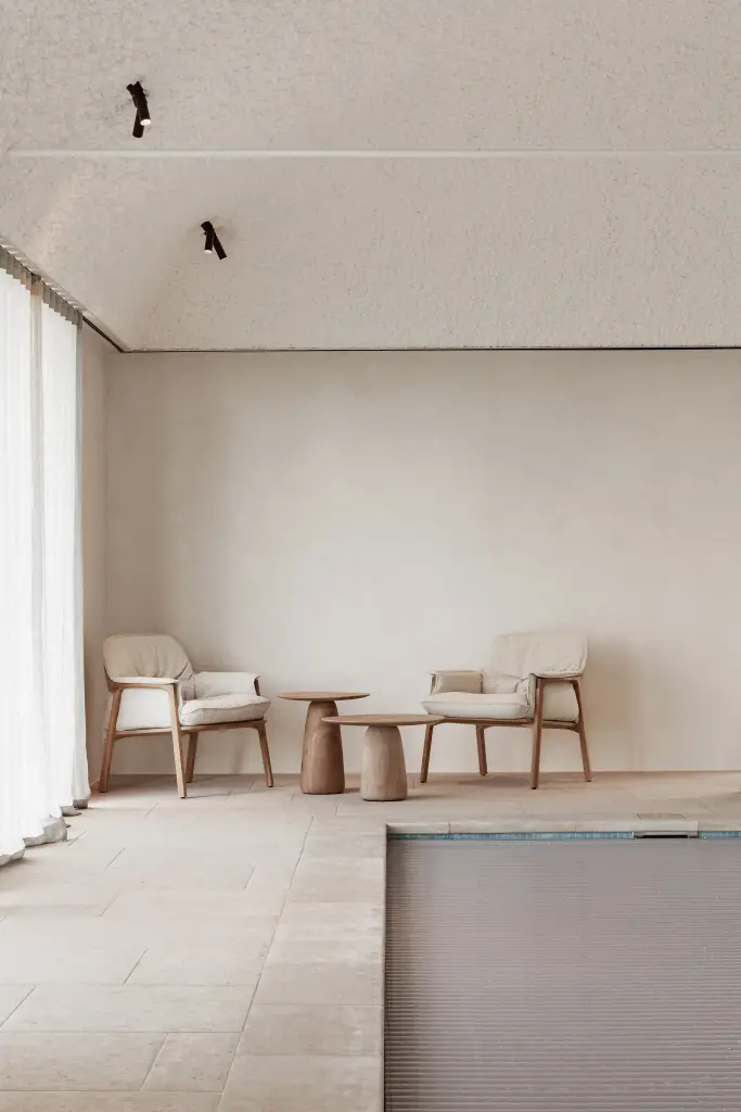 Zithoek met fauteuils en houten bijzettafel naast het zwembad, Schuur in Westkapelle, interieur Laura Calleeuw