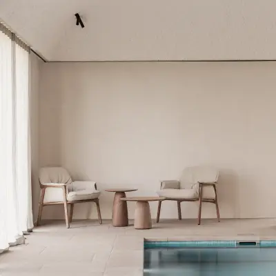 Zithoek met fauteuils en houten bijzettafel naast het zwembad, Schuur in Westkapelle, interieur Laura Calleeuw