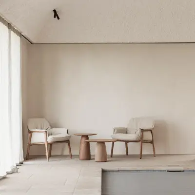 Zithoek met fauteuils en houten bijzettafel naast het zwembad, Schuur in Westkapelle, interieur Laura Calleeuw