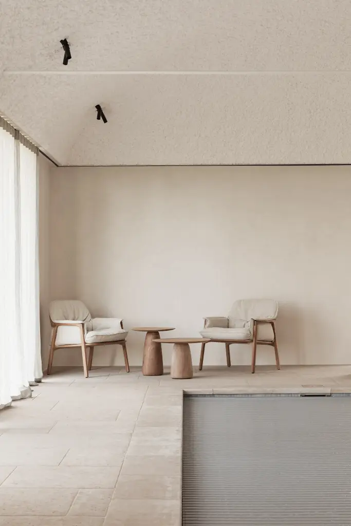 Zithoek met fauteuils en houten bijzettafel naast het zwembad, Schuur in Westkapelle, interieur Laura Calleeuw