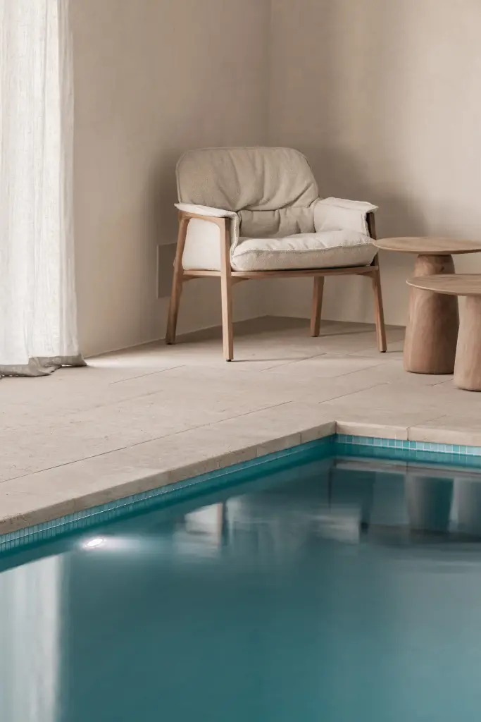 Zithoek met fauteuils en houten bijzettafel naast het zwembad, Schuur in Westkapelle, interieur Laura Calleeuw