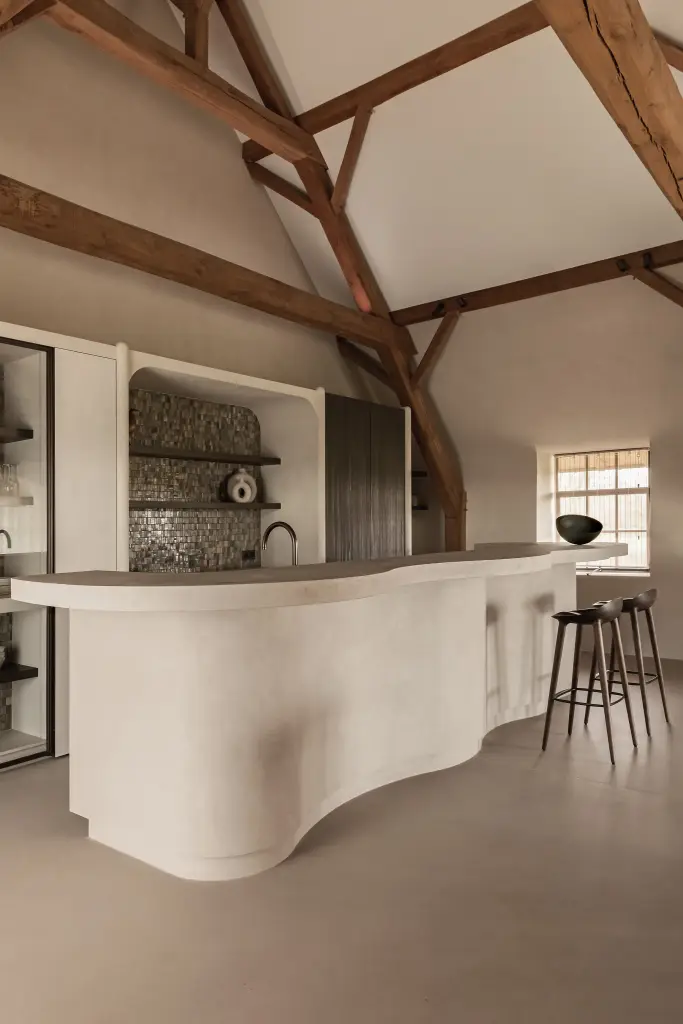Golvend keukeneiland in microcement met verlichte voet en barkrukken, Schuur in Westkapelle, interieur Laura Calleeuw