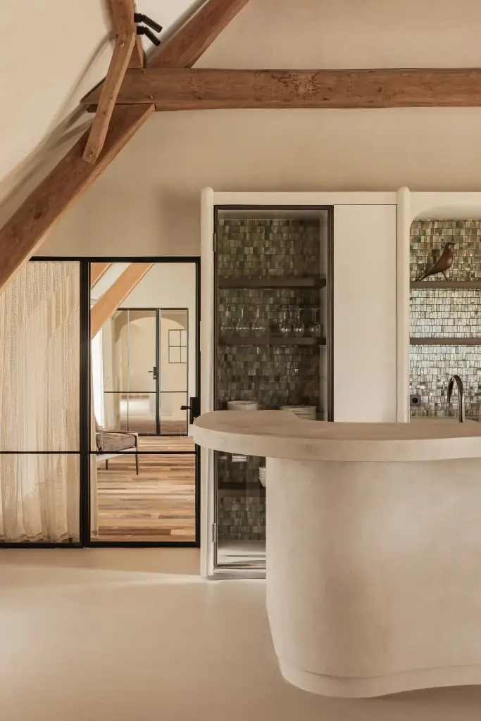 Golvend keukeneiland in microcement met verlichte voet en barkrukken, Schuur in Westkapelle, interieur Laura Calleeuw