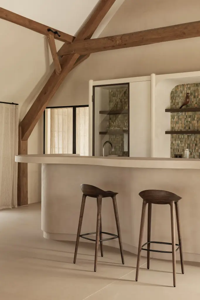 Golvend keukeneiland in microcement met verlichte voet en barkrukken, Schuur in Westkapelle, interieur Laura Calleeuw