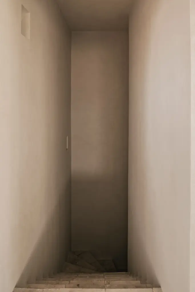 Smalle gang met verlichte nis in microcement, Schuur in Westkapelle, interieur Laura Calleeuw