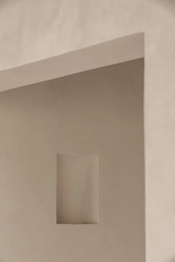 Smalle gang met verlichte nis in microcement, Schuur in Westkapelle, interieur Laura Calleeuw