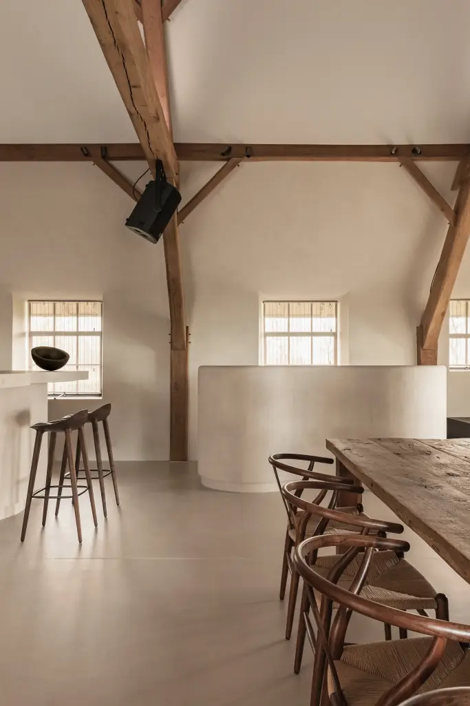 Keuken en eethoek met eikenhouten tafel en wishbone stoelen onder de spanten, Schuur in Westkapelle, interieur Laura Calleeuw