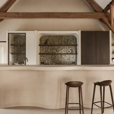 Keukeneiland met barkrukken voor een nis met verlichte planken en tegelrugwand, Schuur in Westkapelle, interieur Laura Calleeuw