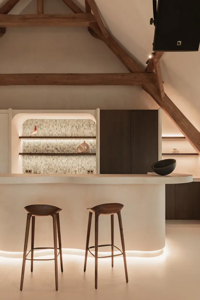 Keukeneiland met barkrukken voor een nis met verlichte planken en tegelrugwand, Schuur in Westkapelle, interieur Laura Calleeuw