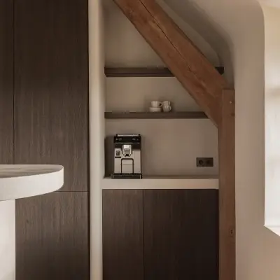 Koffiehoek in een nis met donker eiken kastdeuren en verlichte plank, Schuur in Westkapelle, interieur Laura Calleeuw