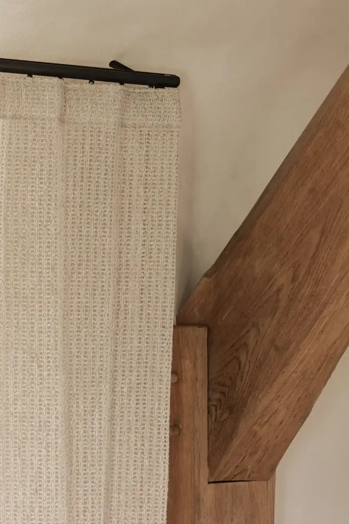 Gebreid linnen gordijn naast een eikenhouten balk, Schuur in Westkapelle, interieur Laura Calleeuw