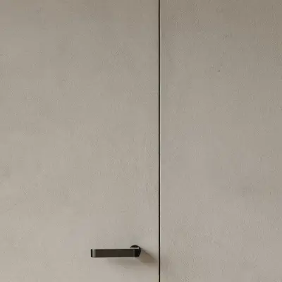 Onzichtbare deur in microcement met zwarte deurklink, Schuur in Westkapelle, interieur Laura Calleeuw