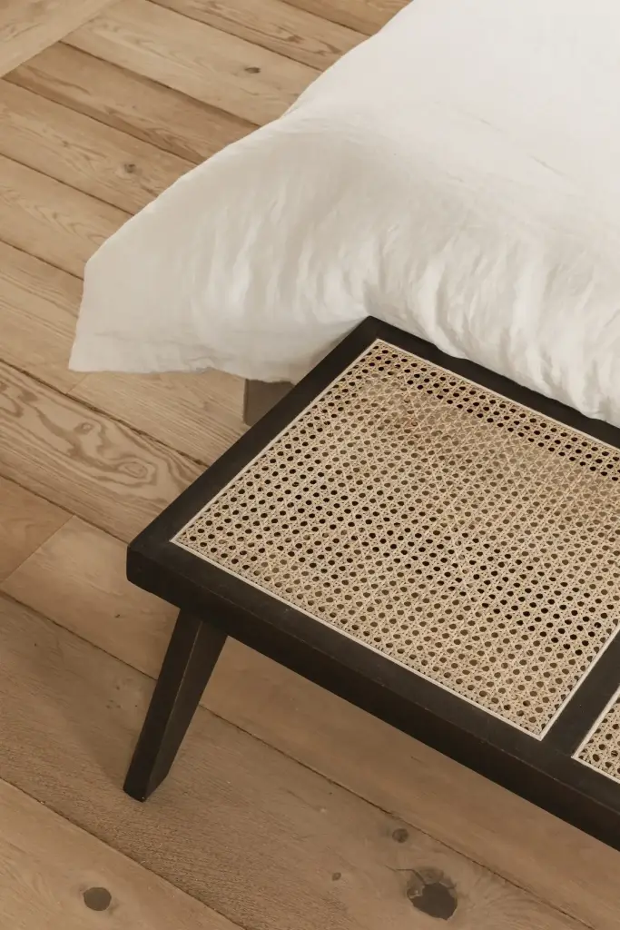 Detail van een rotan bankje op een eikenhouten plankenvloer, Schuur in Westkapelle, interieur Laura Calleeuw