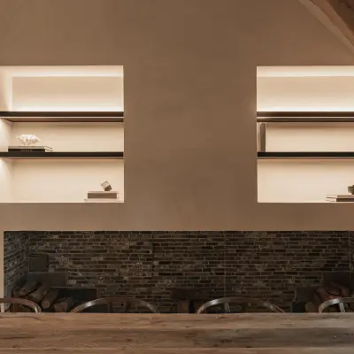 Bakstenen haard met twee nissen met verlichte planken boven een eikenhouten tafel, Schuur in Westkapelle, interieur Laura Calleeuw