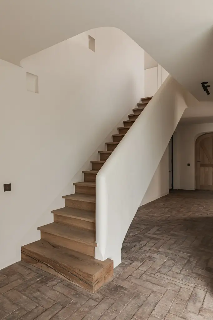Trap met eikenhouten treden, gestucte leuning en vloer in visgraat gebakken baksteen, Schuur in Westkapelle, interieur Laura Calleeuw