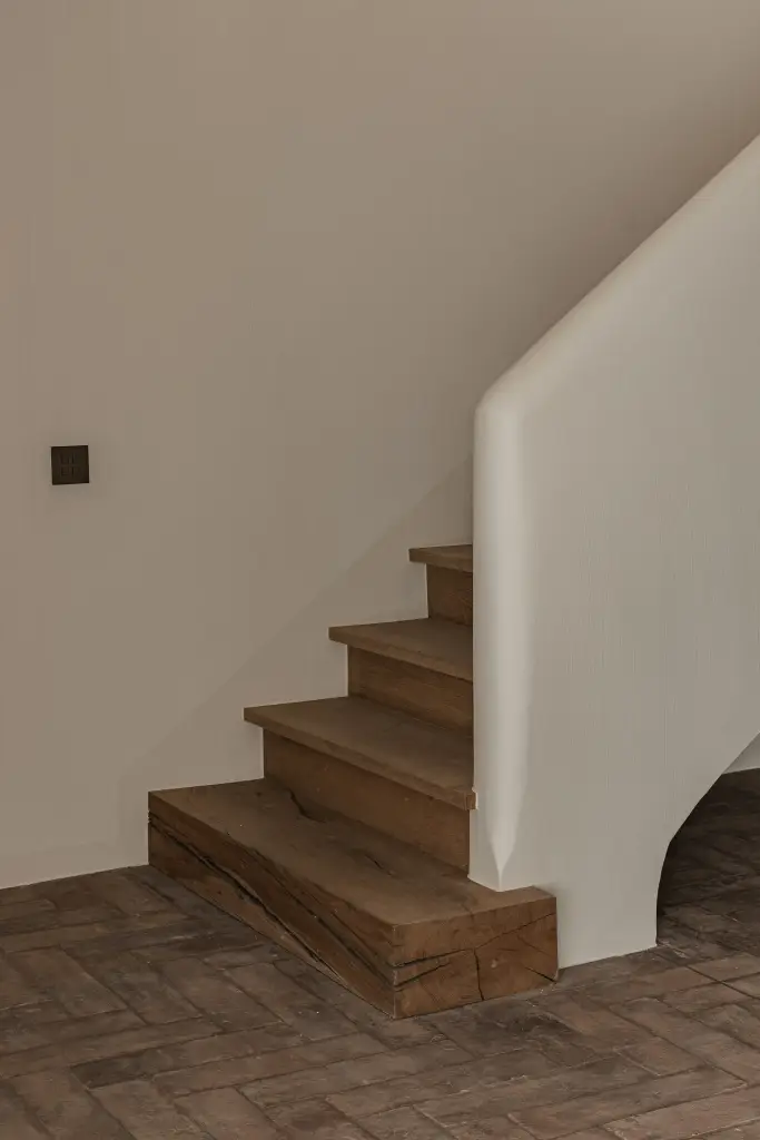 Trap met eikenhouten treden, gestucte leuning en vloer in visgraat gebakken baksteen, Schuur in Westkapelle, interieur Laura Calleeuw