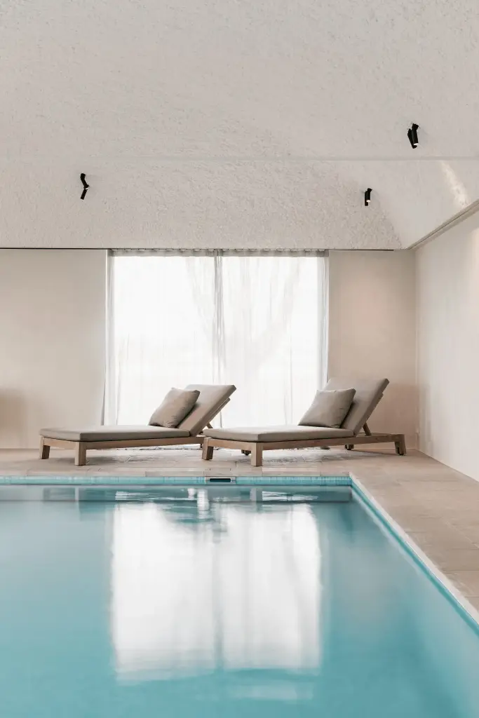 Zwembad met ligstoelen, fauteuils en rolluik over het water, Schuur in Westkapelle, interieur Laura Calleeuw