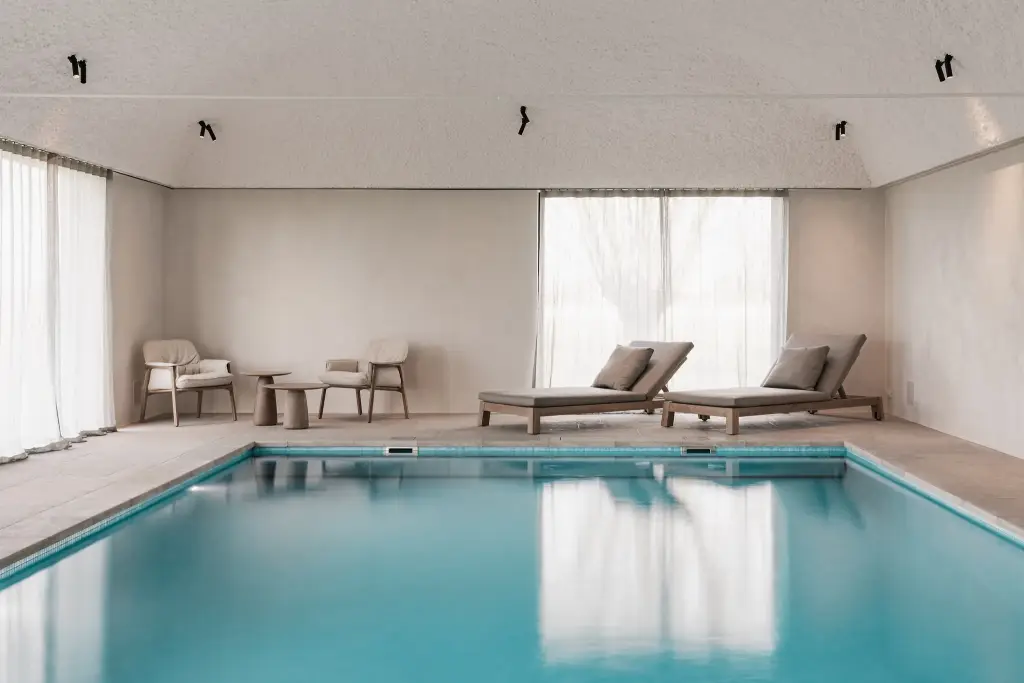 Zwembad met ligstoelen, fauteuils en rolluik over het water, Schuur in Westkapelle, interieur Laura Calleeuw