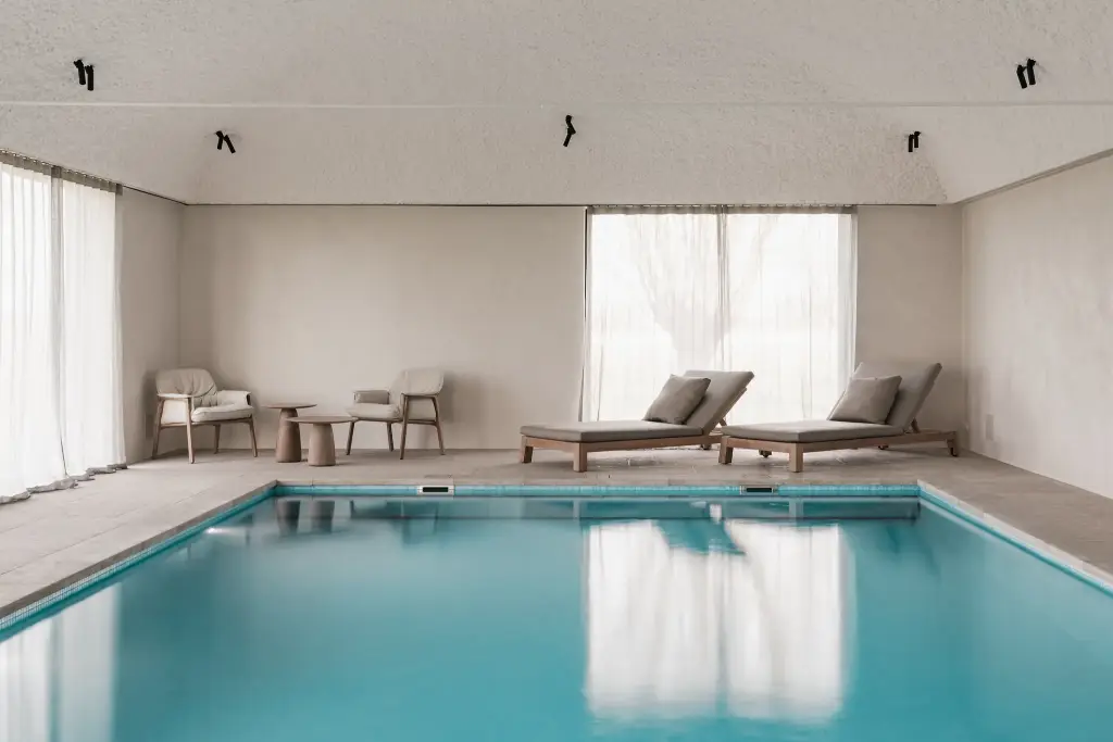 Zwembad met ligstoelen, fauteuils en rolluik over het water, Schuur in Westkapelle, interieur Laura Calleeuw