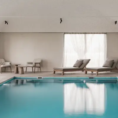 Zwembad met ligstoelen, fauteuils en rolluik over het water, Schuur in Westkapelle, interieur Laura Calleeuw