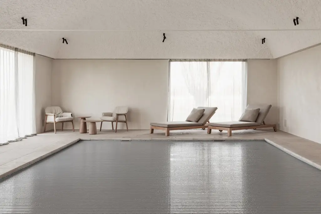 Zwembad met ligstoelen, fauteuils en rolluik over het water, Schuur in Westkapelle, interieur Laura Calleeuw