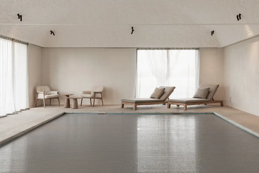 Zwembad met ligstoelen, fauteuils en rolluik over het water, Schuur in Westkapelle, interieur Laura Calleeuw