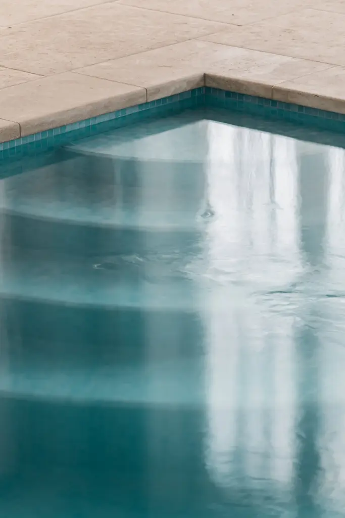 Detail van de zwembadrand in natuursteen met blauwe mozaïektegels, Schuur in Westkapelle, interieur Laura Calleeuw