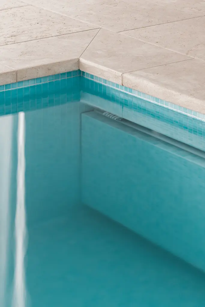 Detail van de zwembadrand in natuursteen met blauwe mozaïektegels, Schuur in Westkapelle, interieur Laura Calleeuw