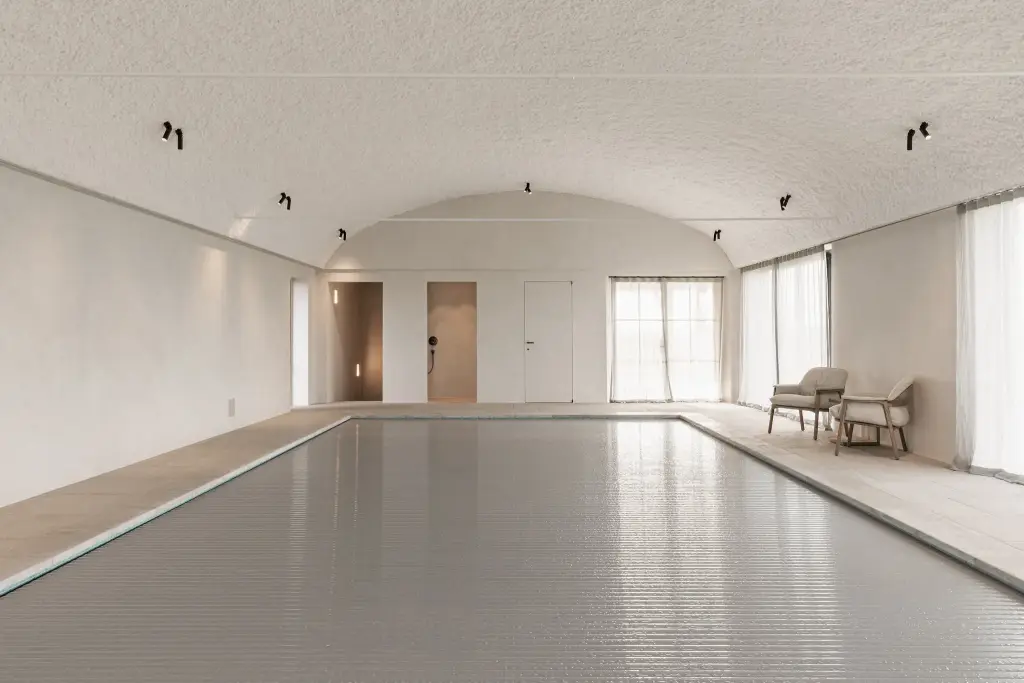 Zwembad onder tongewelf met microcement deuren aan het einde, Schuur in Westkapelle, interieur Laura Calleeuw
