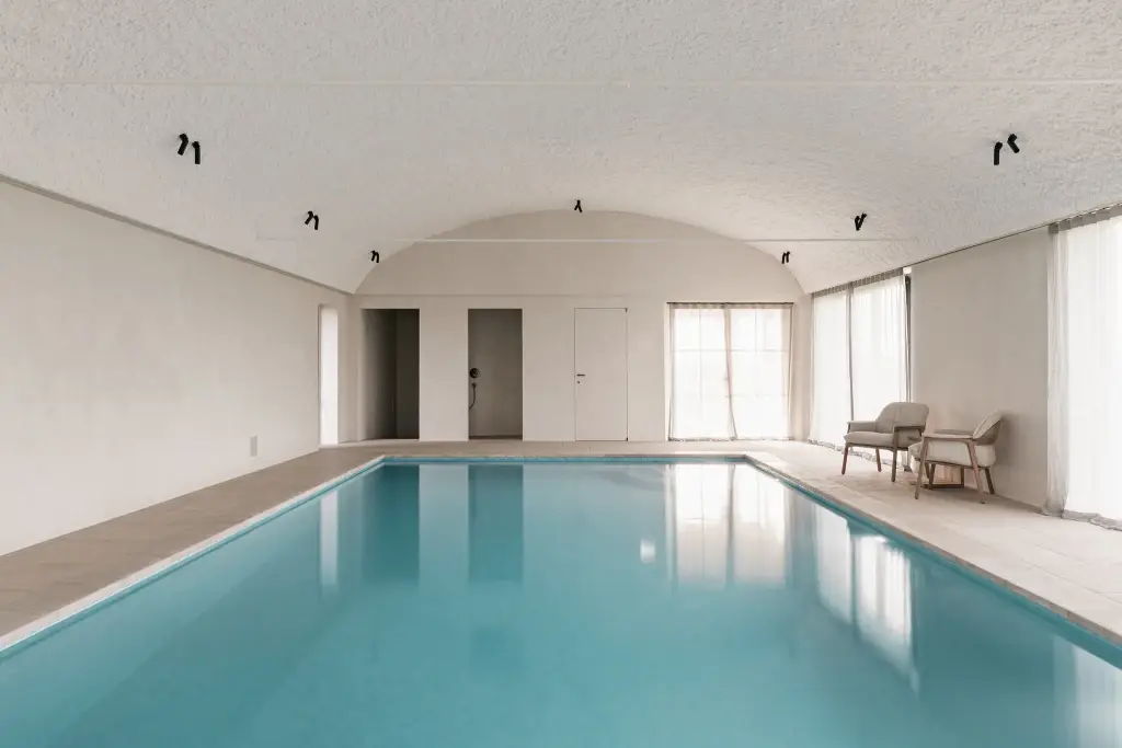 Zwembad onder tongewelf met microcement deuren aan het einde, Schuur in Westkapelle, interieur Laura Calleeuw