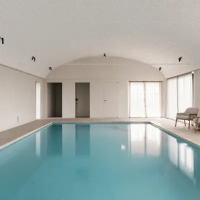 Zwembad onder tongewelf met microcement deuren aan het einde, Schuur in Westkapelle, interieur Laura Calleeuw