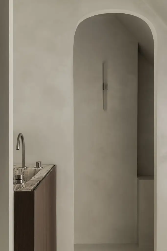 Boogvormige doorgang in gepleisterde wanden met een wastafel op houten onderkast, Het Zoute Schorre, interieur Laura Calleeuw