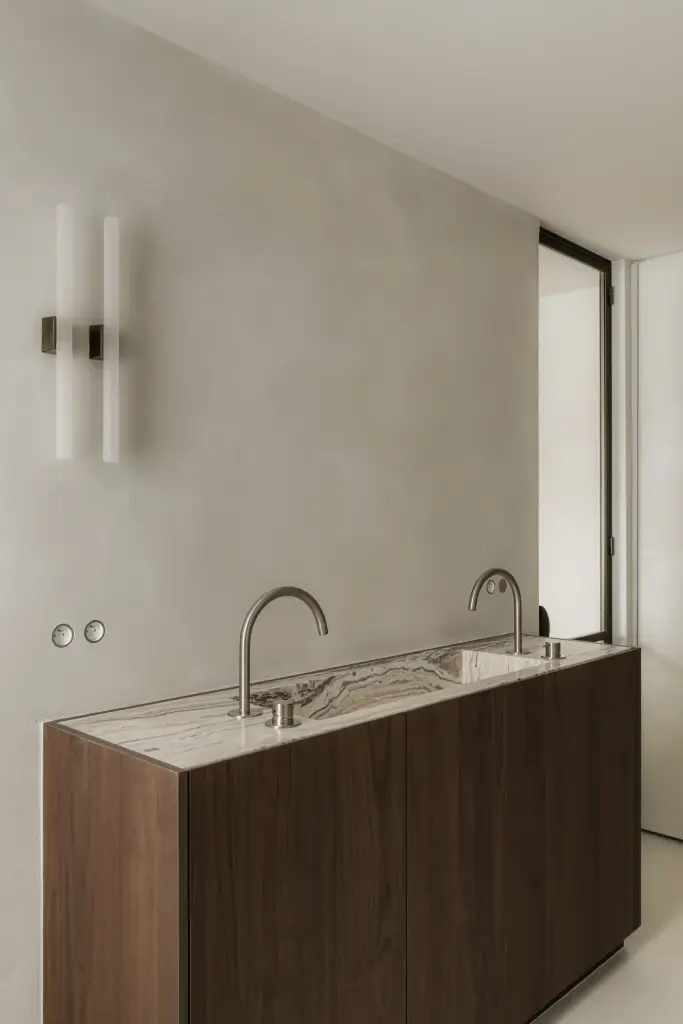 Dubbele wastafel met kranen op een houten onderkast, met een wandlamp, Het Zoute Schorre, interieur Laura Calleeuw