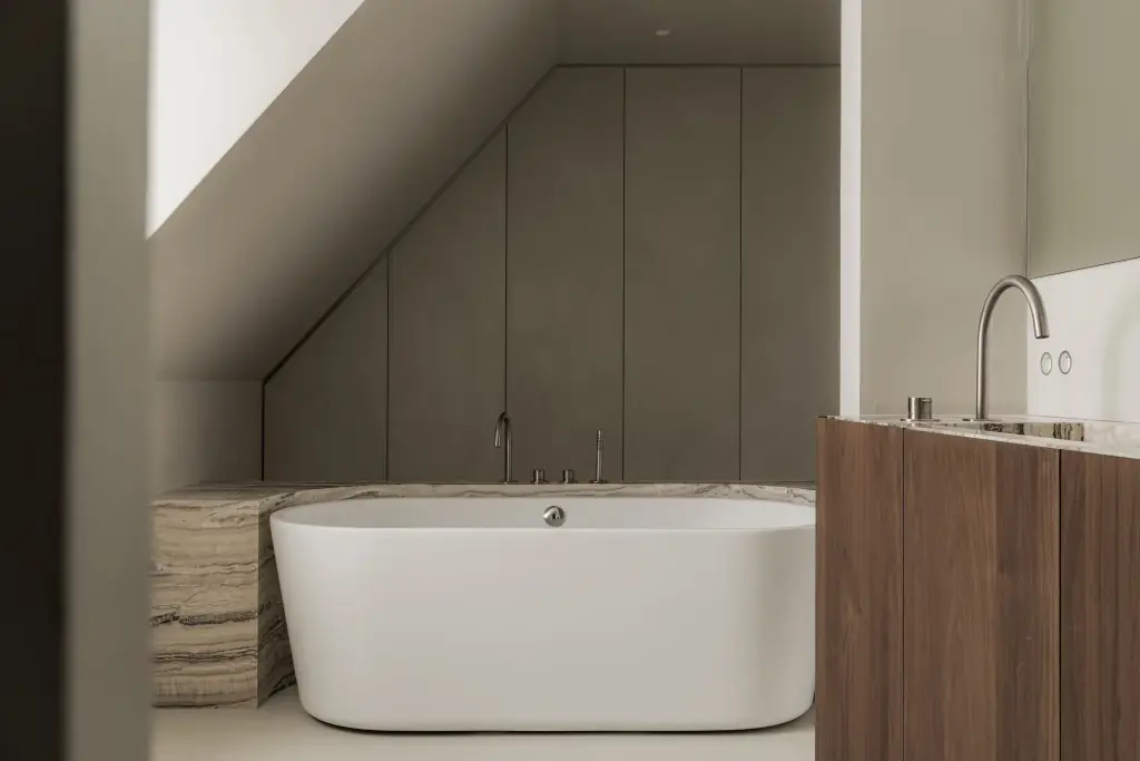Badkamer met vrijstaand bad, kastenwand onder de dakhelling en een houten wastafelmeubel, Het Zoute Schorre, interieur Laura Calleeuw