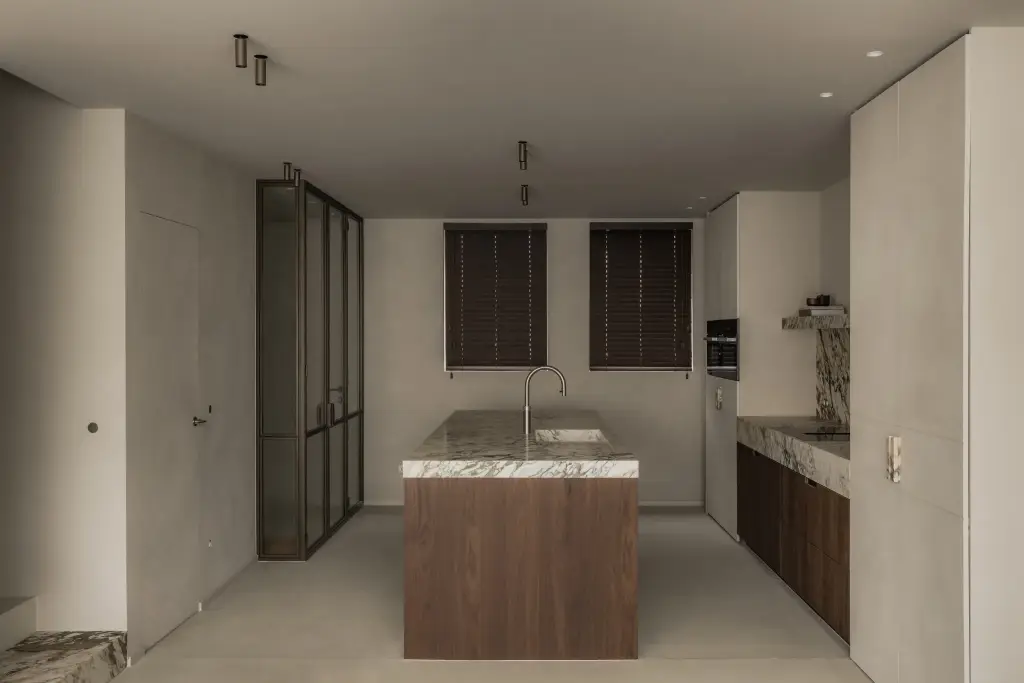 Keuken met kookeiland in het midden en stalen glasdeuren aan de linkerkant, Het Zoute Schorre, interieur Laura Calleeuw