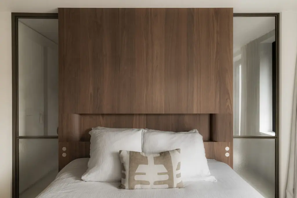 Bed met hoog houten hoofdbord tussen stalen glaswanden, Het Zoute Schorre, interieur Laura Calleeuw