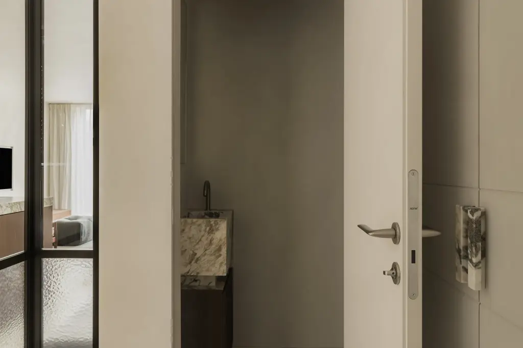 Open deur naar het toilet met natuurstenen wastafel, naast een kastdeur met natuurstenen handgreep, Het Zoute Schorre, interieur Laura Calleeuw