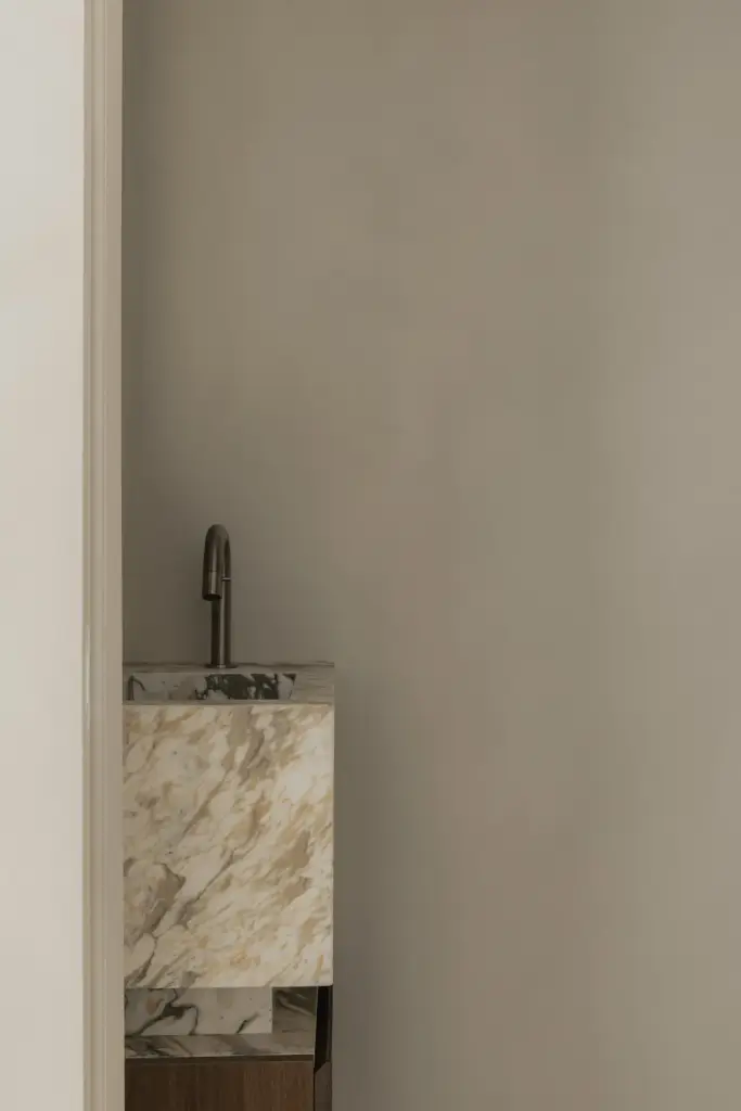 Natuurstenen wastafel met kraan in een nis met gladde pleisterwanden, Het Zoute Schorre, interieur Laura Calleeuw